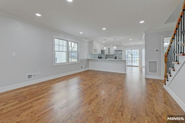 unfurnished living room featuring light hardwood / wood-style floors and crown molding