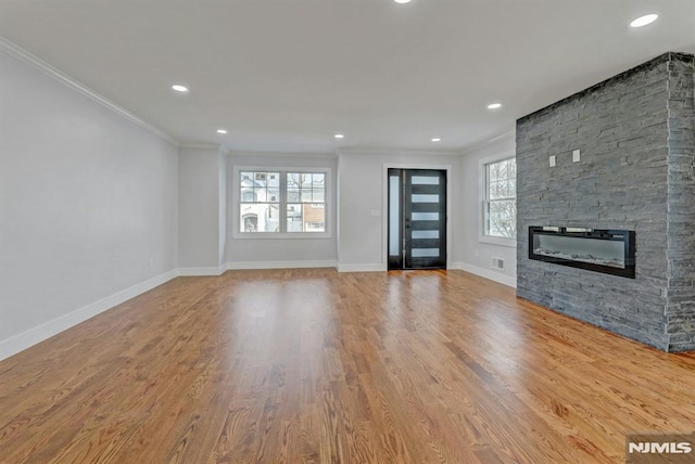 unfurnished living room with a fireplace, crown molding, and light hardwood / wood-style flooring