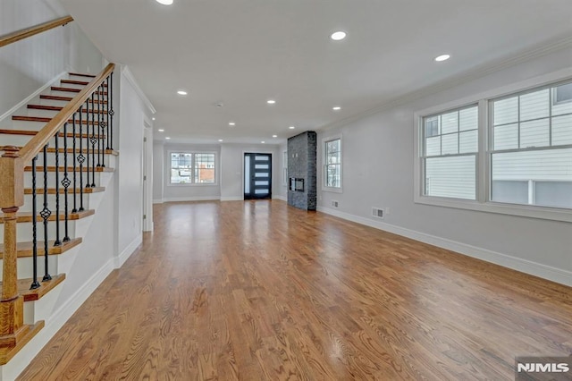 unfurnished living room with light hardwood / wood-style flooring, crown molding, and a fireplace