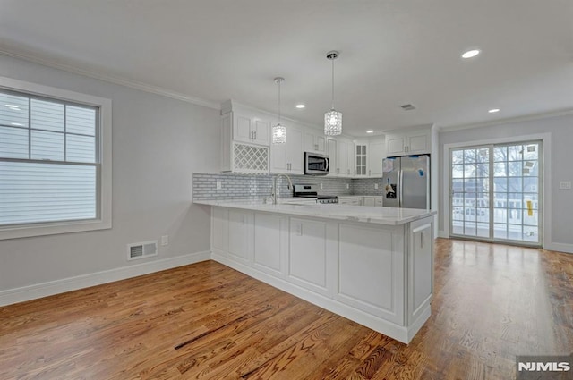 kitchen featuring decorative light fixtures, kitchen peninsula, appliances with stainless steel finishes, and white cabinetry