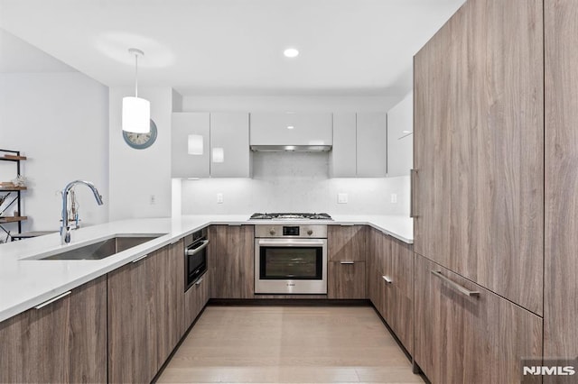 kitchen with sink, hanging light fixtures, stainless steel appliances, ventilation hood, and white cabinets