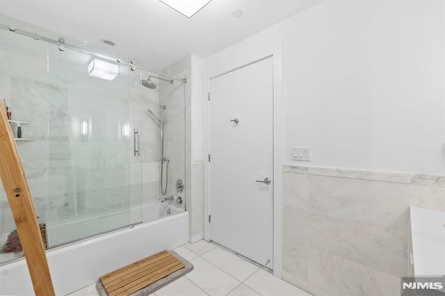 bathroom featuring tile patterned floors, shower / bath combination with glass door, and tile walls