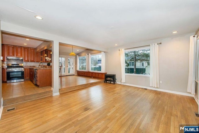 unfurnished living room featuring sink, light hardwood / wood-style flooring, and french doors