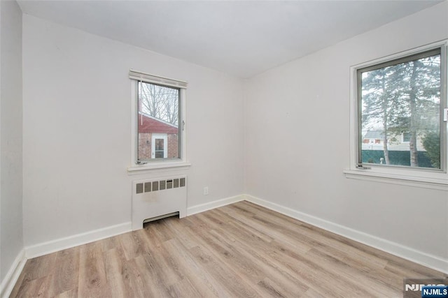 unfurnished room with light hardwood / wood-style floors and radiator