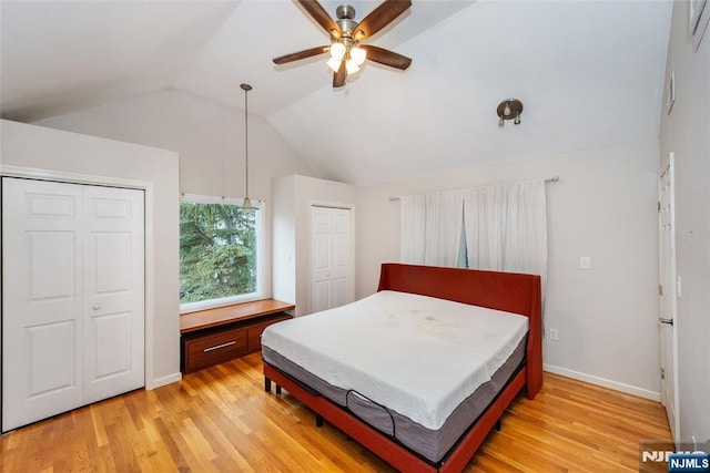 bedroom featuring ceiling fan, vaulted ceiling, multiple closets, and light hardwood / wood-style flooring