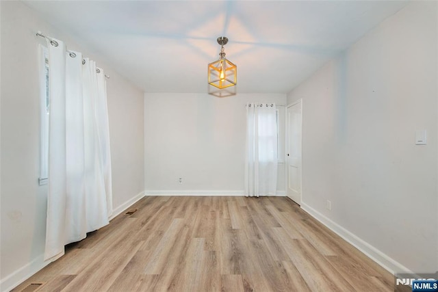 empty room featuring light hardwood / wood-style flooring and a notable chandelier