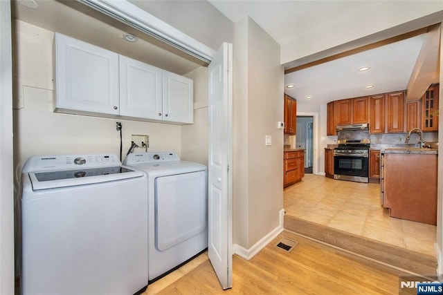 laundry area featuring light wood-type flooring, separate washer and dryer, and sink