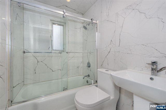 full bathroom with toilet, bath / shower combo with glass door, and sink