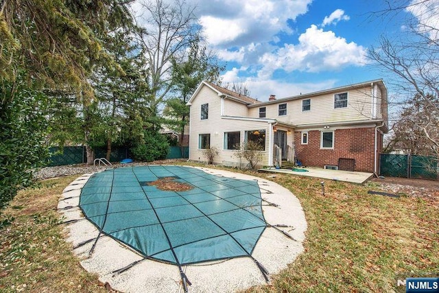 rear view of property with a yard, a patio area, and a covered pool