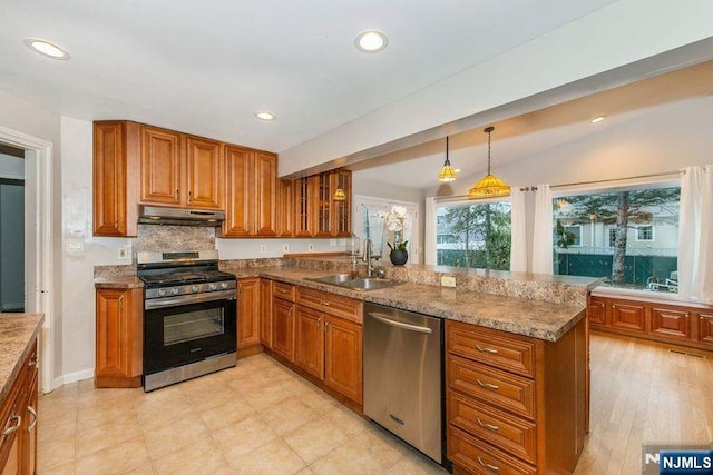 kitchen with kitchen peninsula, stainless steel appliances, tasteful backsplash, decorative light fixtures, and sink