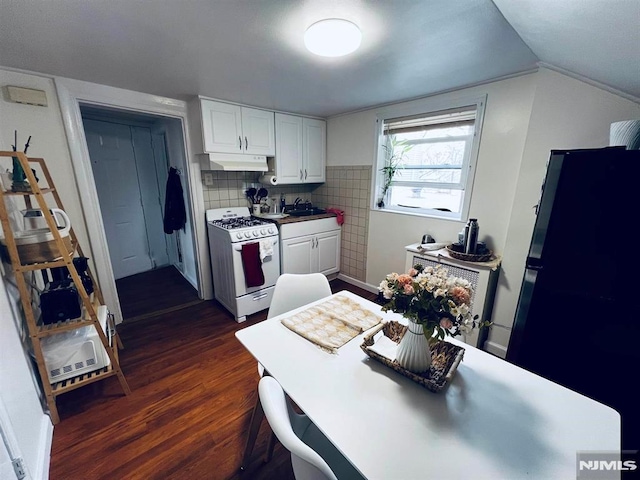 kitchen with dark wood-type flooring, white cabinets, black fridge, sink, and white gas range