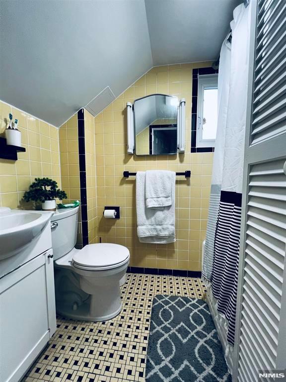 bathroom with vanity, tile walls, and vaulted ceiling