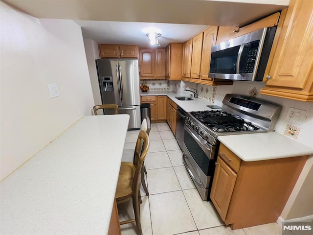 kitchen with decorative backsplash, light tile patterned floors, stainless steel appliances, and sink