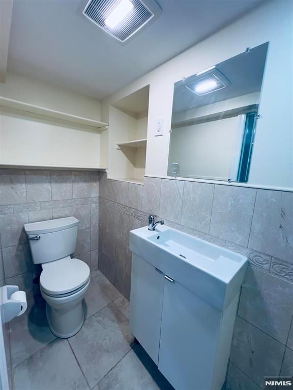 bathroom with vanity, toilet, and tile walls