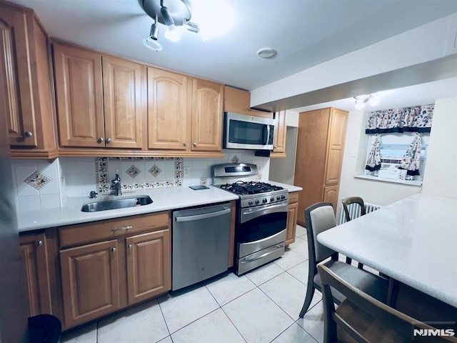 kitchen with tasteful backsplash, sink, light tile patterned flooring, and appliances with stainless steel finishes