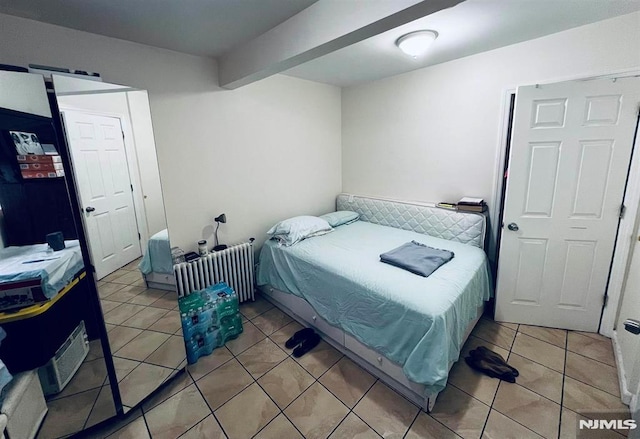 bedroom with tile patterned flooring, beam ceiling, and radiator