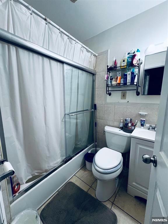 full bathroom with tasteful backsplash, tile patterned floors, vanity, tile walls, and toilet