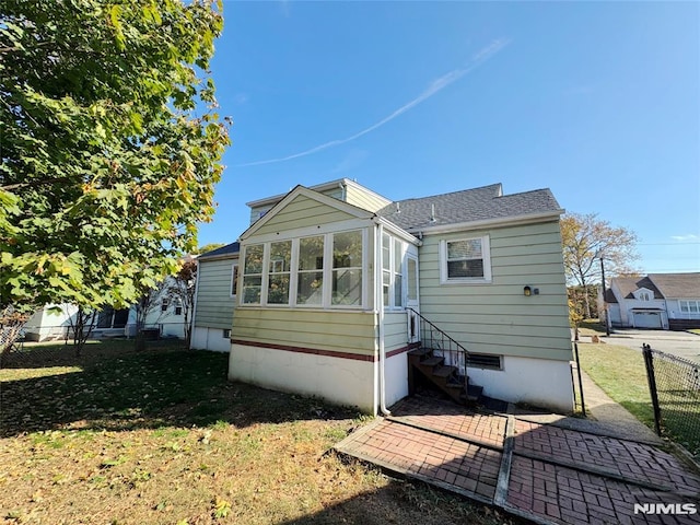 rear view of property with a lawn and a sunroom