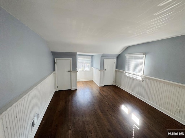 bonus room with dark hardwood / wood-style flooring and vaulted ceiling