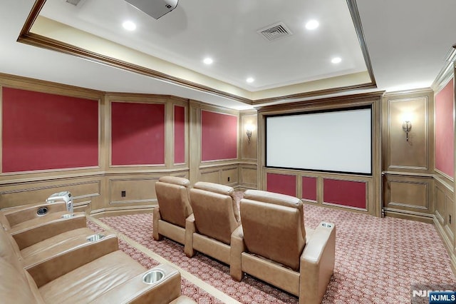 cinema room featuring crown molding, light colored carpet, and a tray ceiling