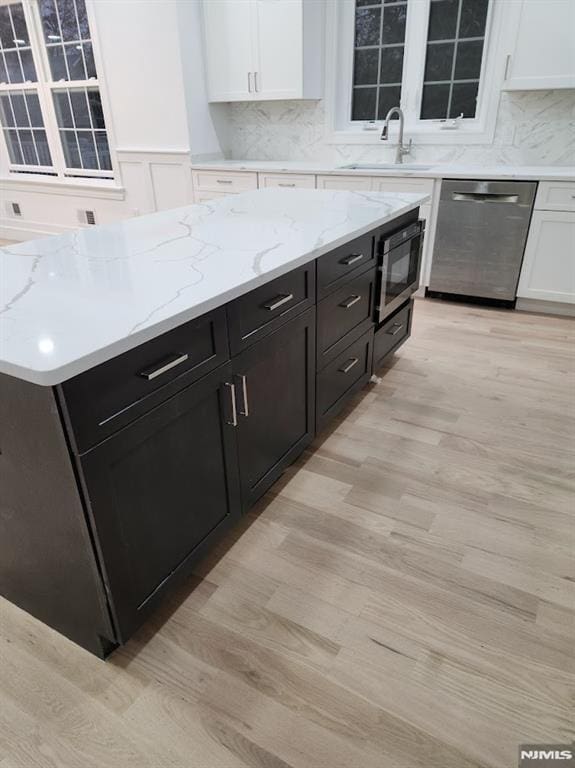 kitchen with dishwasher, sink, light hardwood / wood-style flooring, built in microwave, and tasteful backsplash