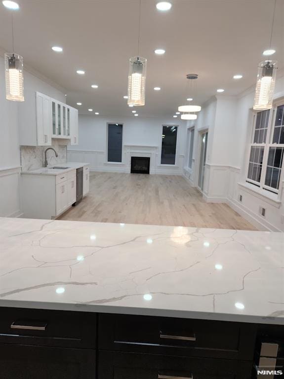 kitchen featuring pendant lighting, dishwasher, white cabinetry, and sink