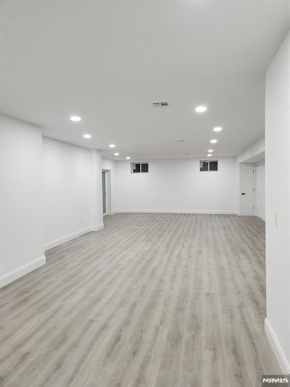 finished basement with light wood-style floors, visible vents, baseboards, and recessed lighting