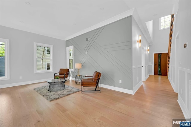 sitting room featuring light wood-type flooring, baseboards, and a decorative wall