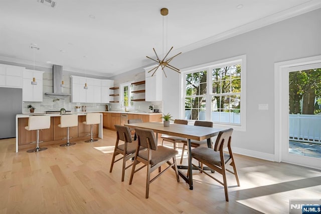 dining room with a chandelier, light wood-style floors, plenty of natural light, and ornamental molding