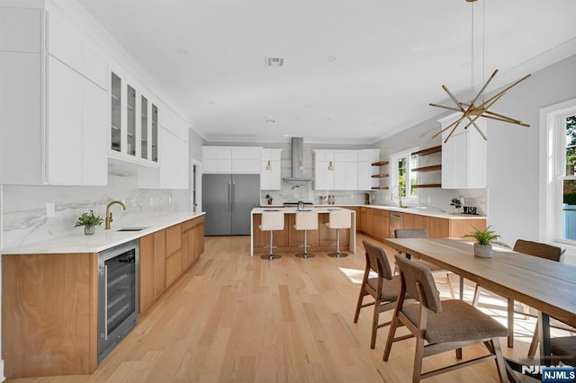 kitchen with stainless steel appliances, white cabinets, a kitchen island, and wall chimney range hood