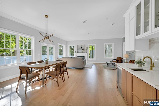 dining space featuring light wood finished floors, a fireplace, visible vents, and baseboards