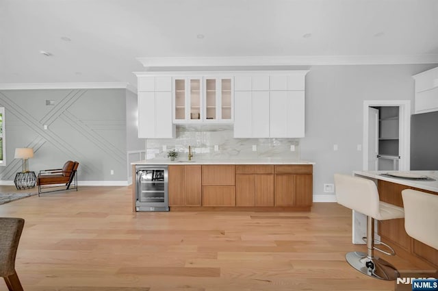 kitchen featuring glass insert cabinets, wine cooler, light countertops, and white cabinetry