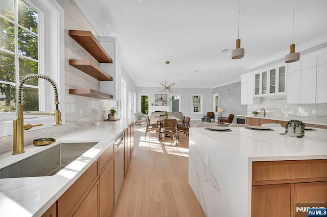 kitchen with glass insert cabinets, pendant lighting, white cabinets, and a sink