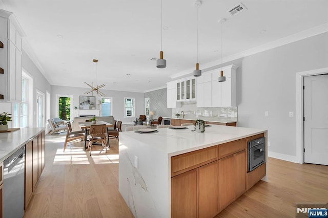 kitchen with a large island, visible vents, white cabinetry, and stainless steel dishwasher