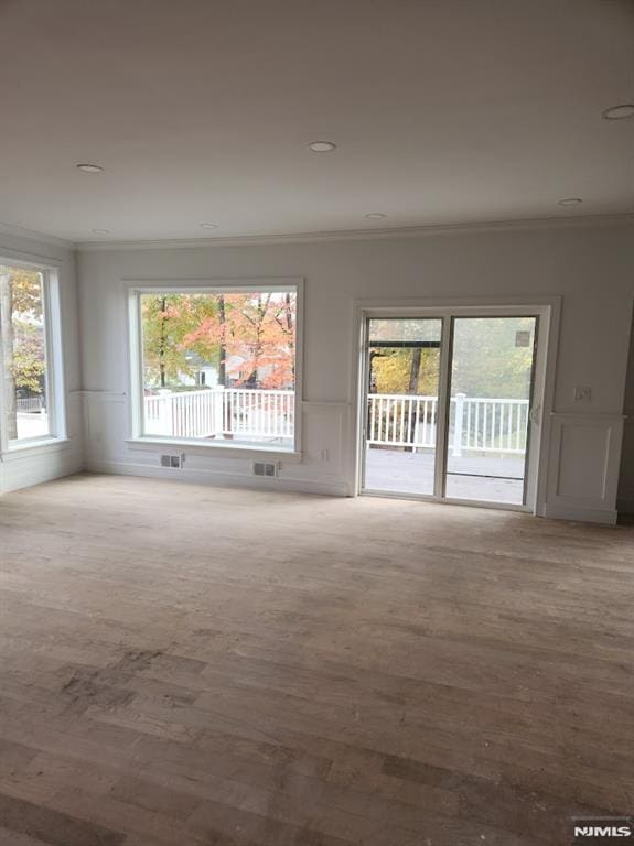 spare room featuring crown molding and light wood-type flooring