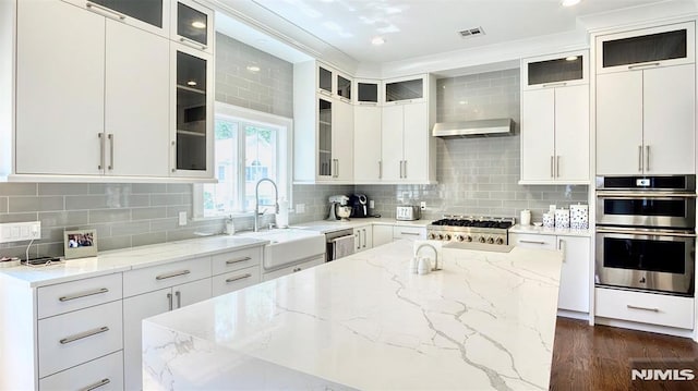 kitchen featuring sink, stainless steel appliances, white cabinetry, decorative backsplash, and light stone countertops