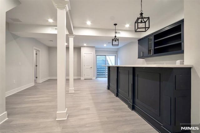 kitchen featuring hanging light fixtures, light wood-type flooring, kitchen peninsula, and ornate columns