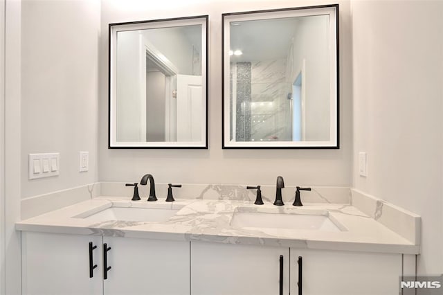 bathroom with a tile shower and vanity