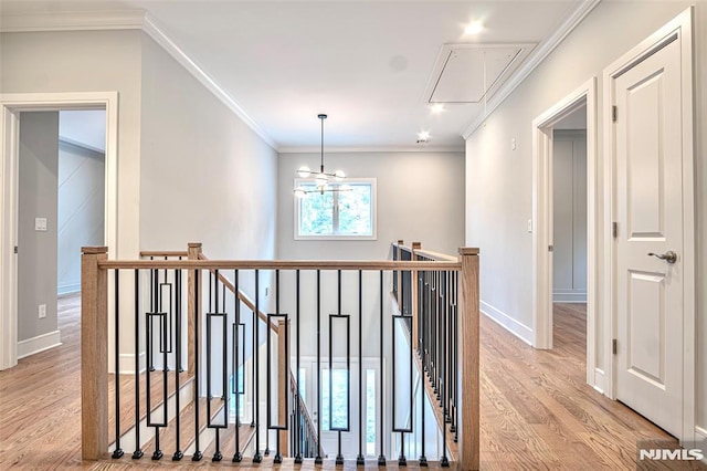 hallway featuring a notable chandelier, light wood-type flooring, and ornamental molding