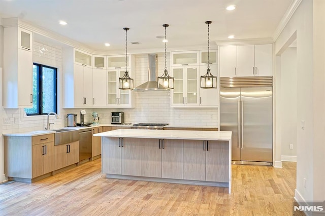 kitchen with a large island, stainless steel appliances, decorative light fixtures, and wall chimney exhaust hood