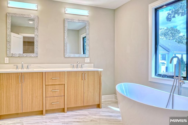 bathroom with a bath, vanity, and plenty of natural light