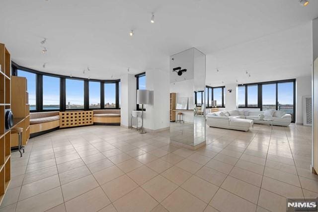 unfurnished living room featuring ceiling fan, a healthy amount of sunlight, and light tile patterned flooring