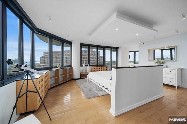 bedroom with a wall of windows and light hardwood / wood-style flooring