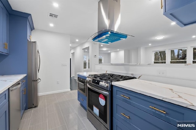 kitchen with light stone countertops, appliances with stainless steel finishes, island range hood, and blue cabinets