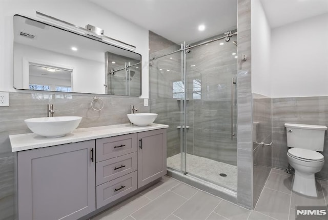 bathroom with tile patterned flooring, vanity, an enclosed shower, and toilet