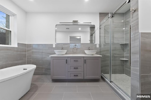 bathroom featuring tile patterned floors, vanity, separate shower and tub, and tile walls