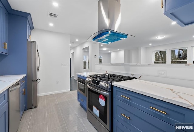 kitchen with blue cabinetry, island exhaust hood, light stone countertops, and stainless steel appliances