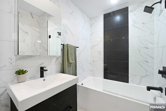 bathroom with shower / tub combination, tasteful backsplash, vanity, and tile walls