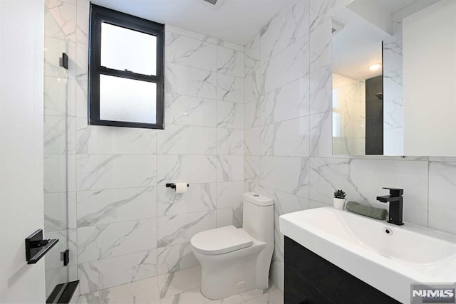 bathroom with vanity, toilet, and tile walls