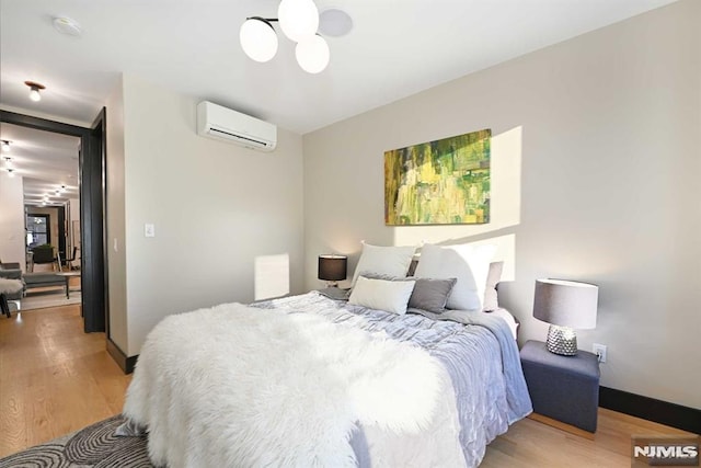 bedroom featuring a wall mounted air conditioner and light wood-type flooring